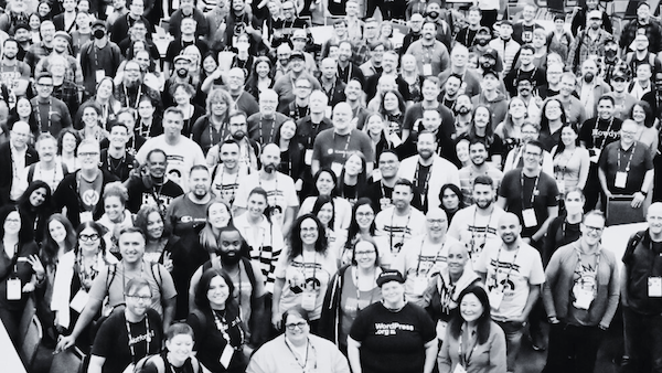 close-crop high contrast black and white overhead shot of a few hundred people smiling at the camera